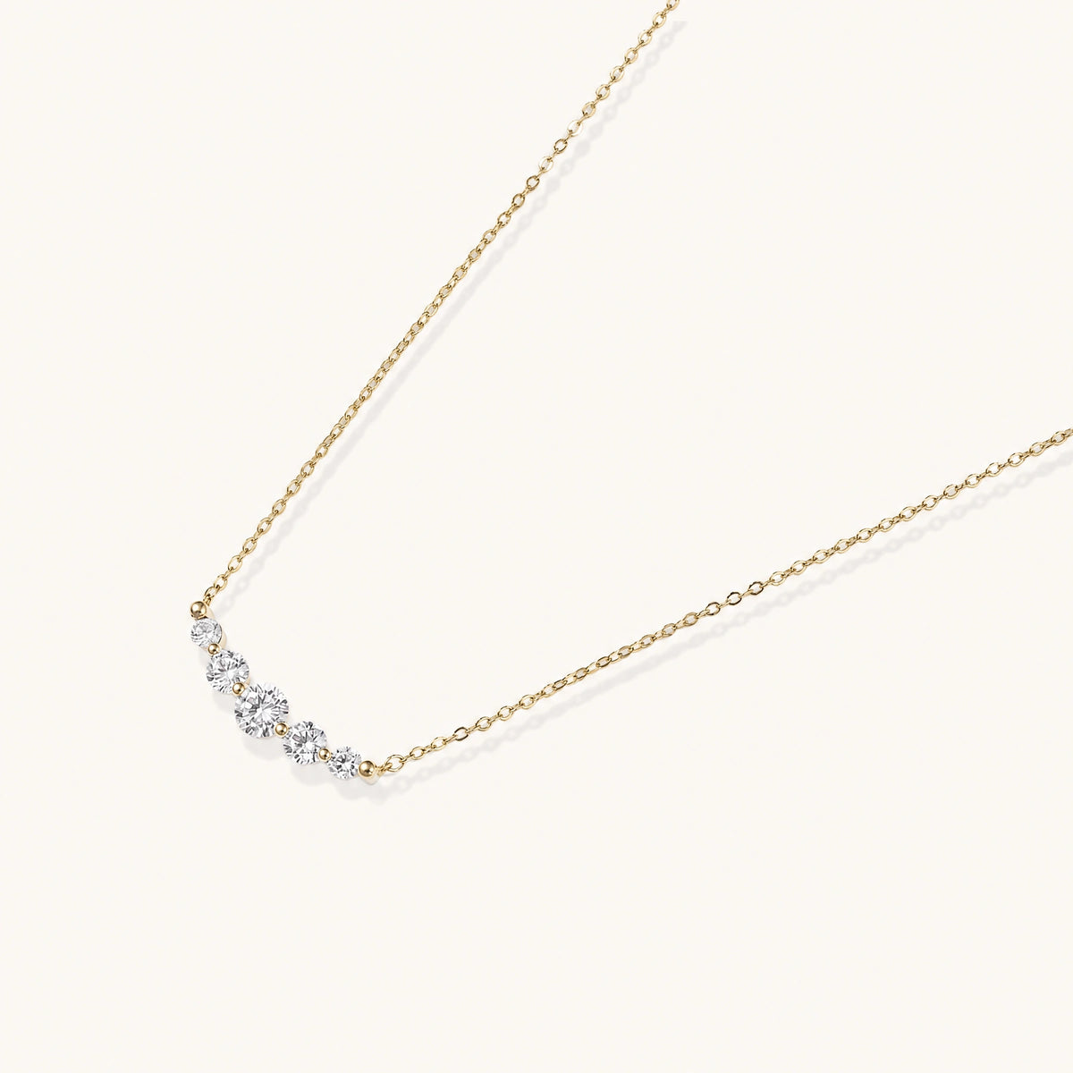Delicate 14K gold-plated necklace with five graduated zirconia stones arranged in a curved arc on fine chain