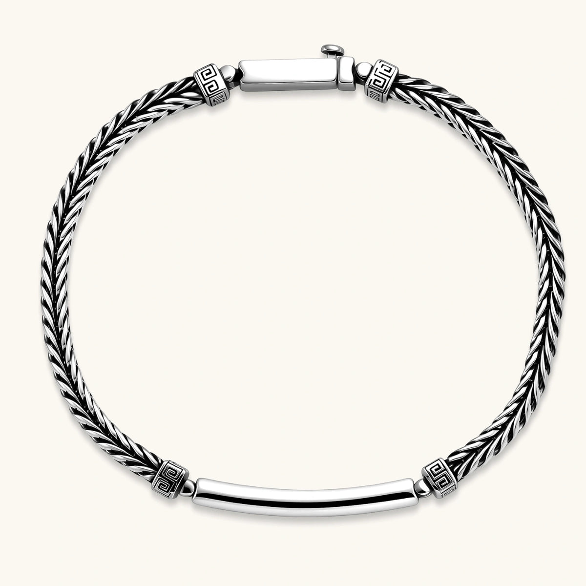 Antique silver plated chain bracelet with a Greek key engraved ID bar and patterned spacer beads on a cream background.