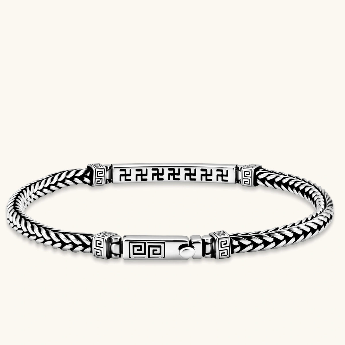 Antique silver plated chain bracelet with a Greek key engraved ID bar and patterned spacer beads on a cream background.